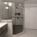 Modern bathroom with glass shower and marble walls.