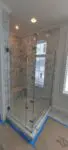 Modern glass shower enclosure in a bathroom under renovation.