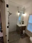 Modern bathroom with white subway tiles, a glass shower door, and a sleek vanity.