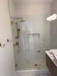 Modern bathroom with glass shower enclosure and gold fixtures.